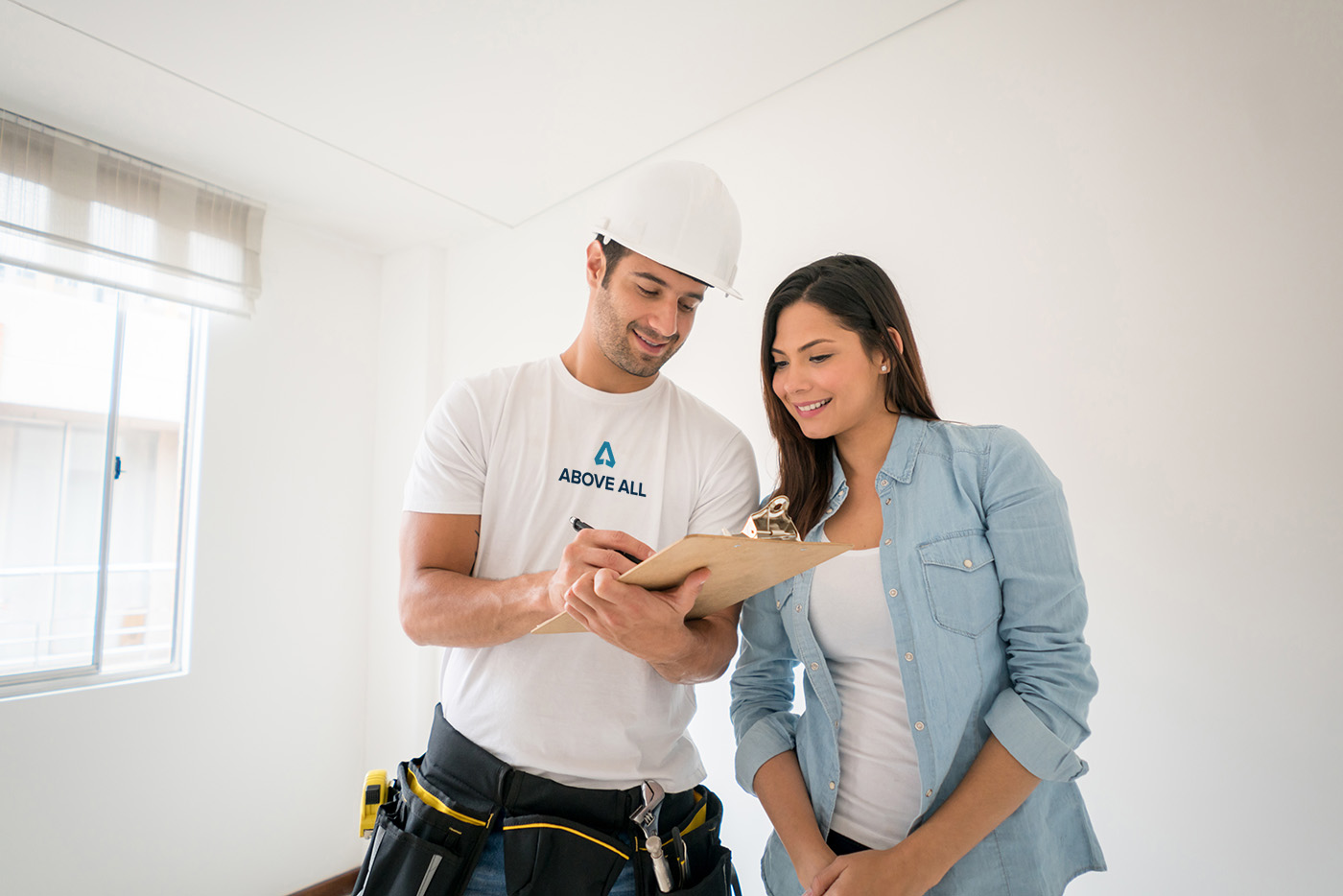 Above All contractor reviews paperwork with a homeowner in a bright room