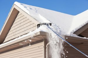 Out of sight worker removes snow from roof with roof rake