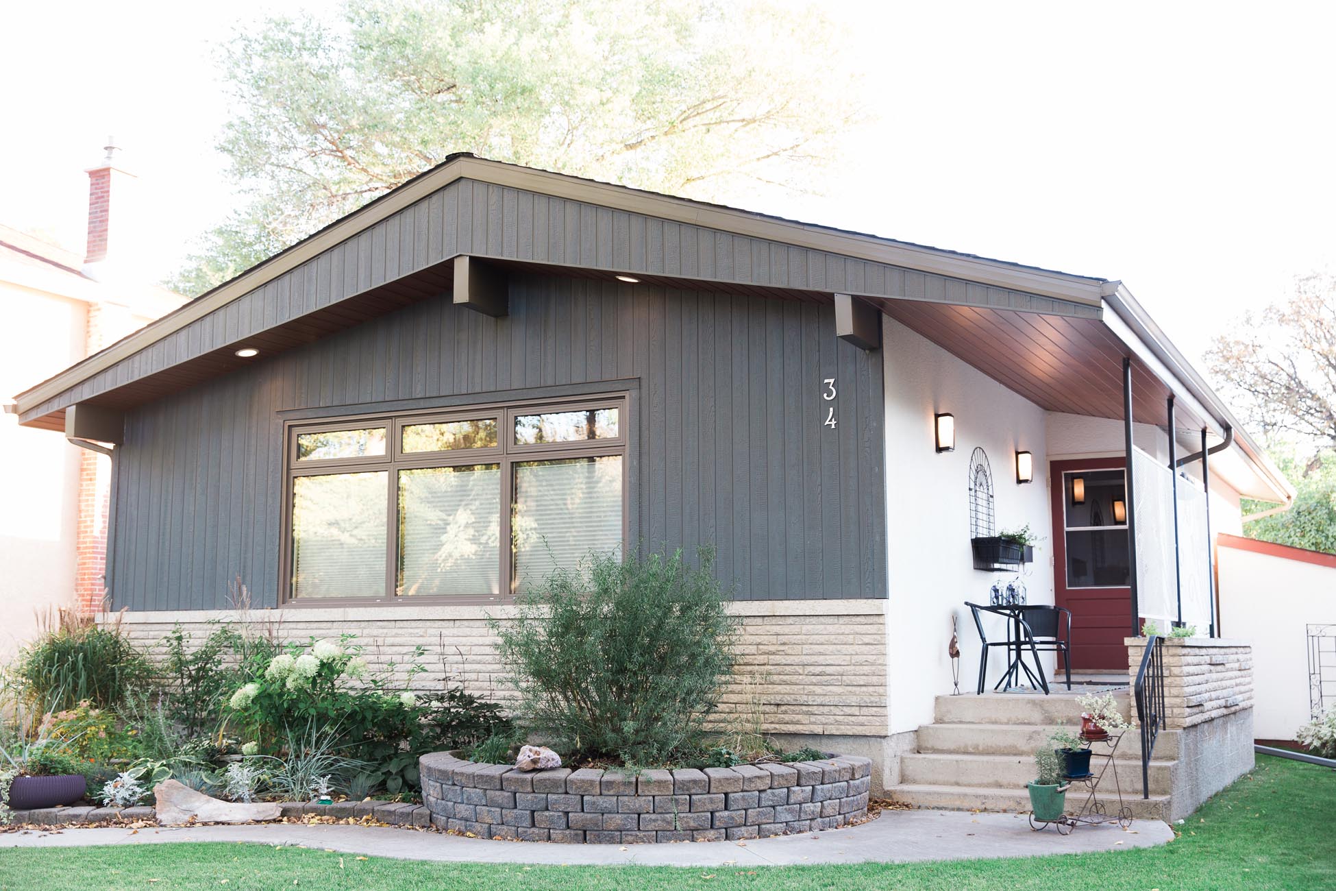 Modern home with gray siding, red door, and landscaped front yard