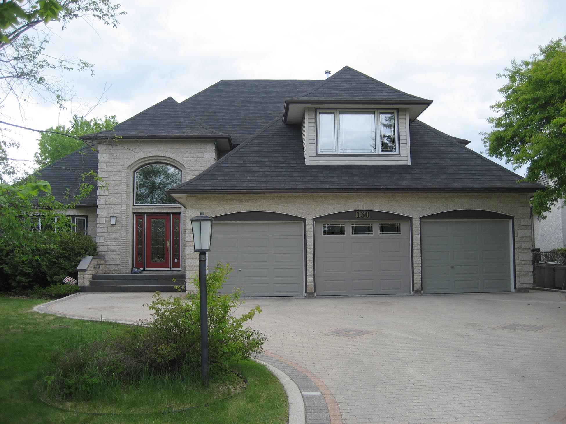 Large house with three-car garage and stone accents.