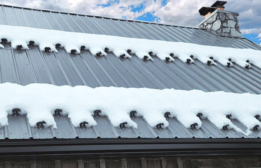 Metal roof with snow guards holding snow in place near chimney