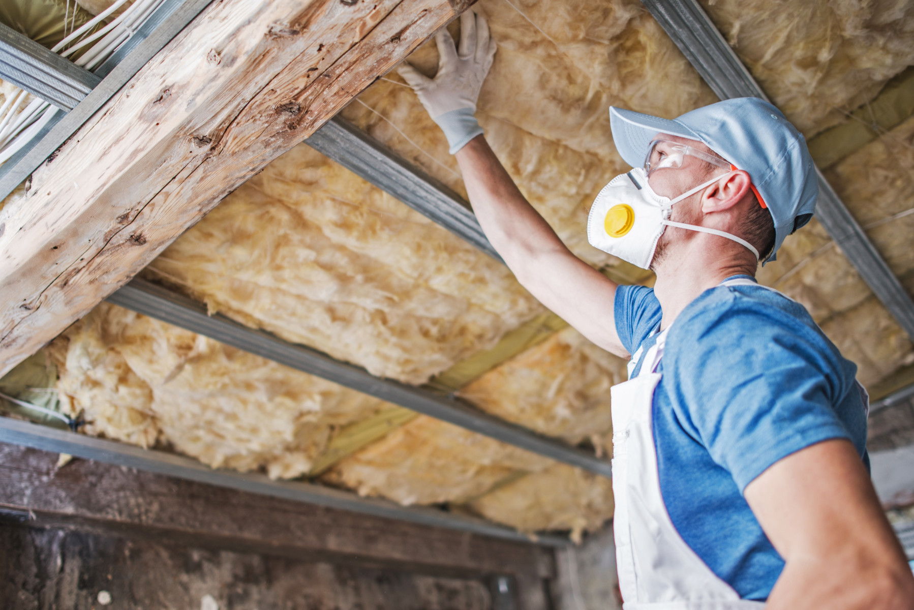 Old Roof Insulation. Caucasian Male Insulation Worker Inspecting Aged Roof Insulation.