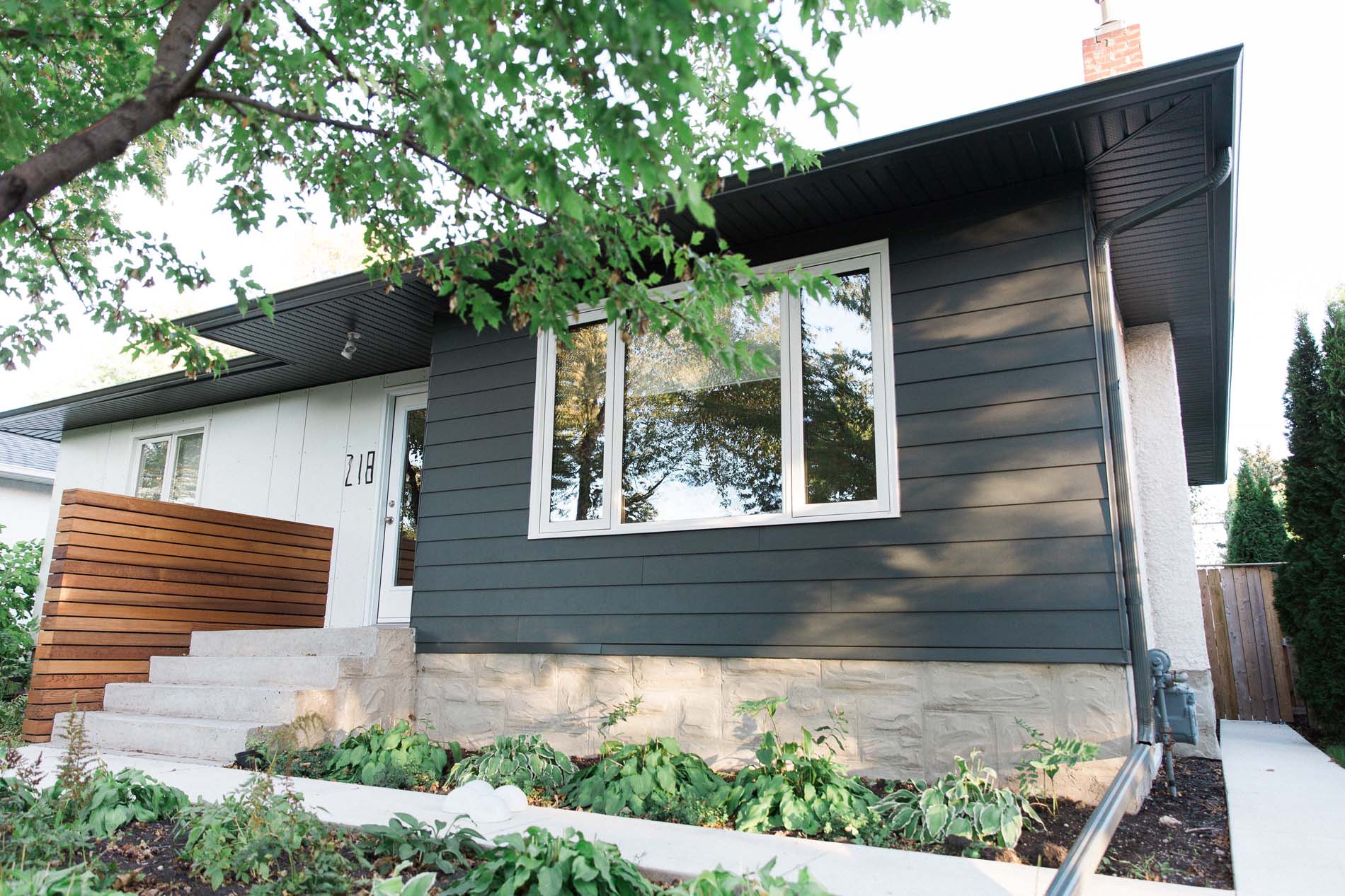 Modern home with dark siding, wood accents, and fresh landscaping