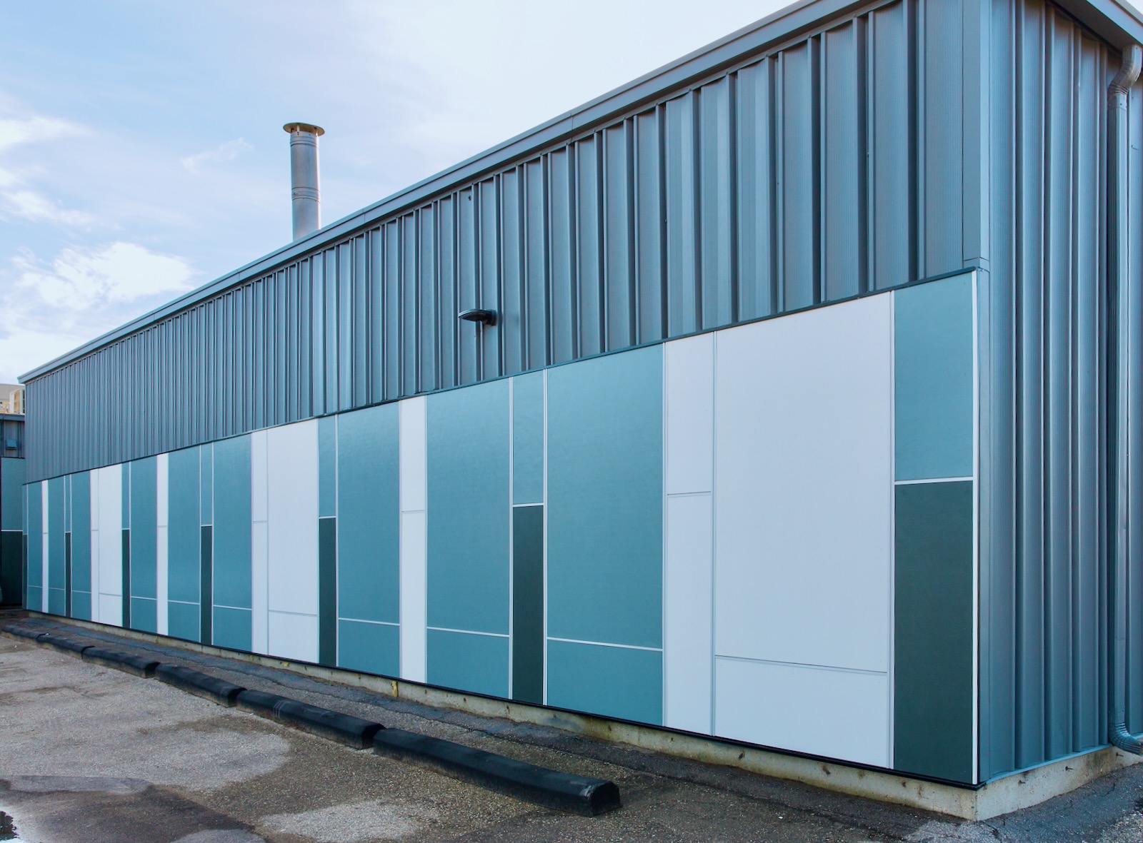 Commercial building exterior with blue and white metal wall panels and vertical metal siding.
