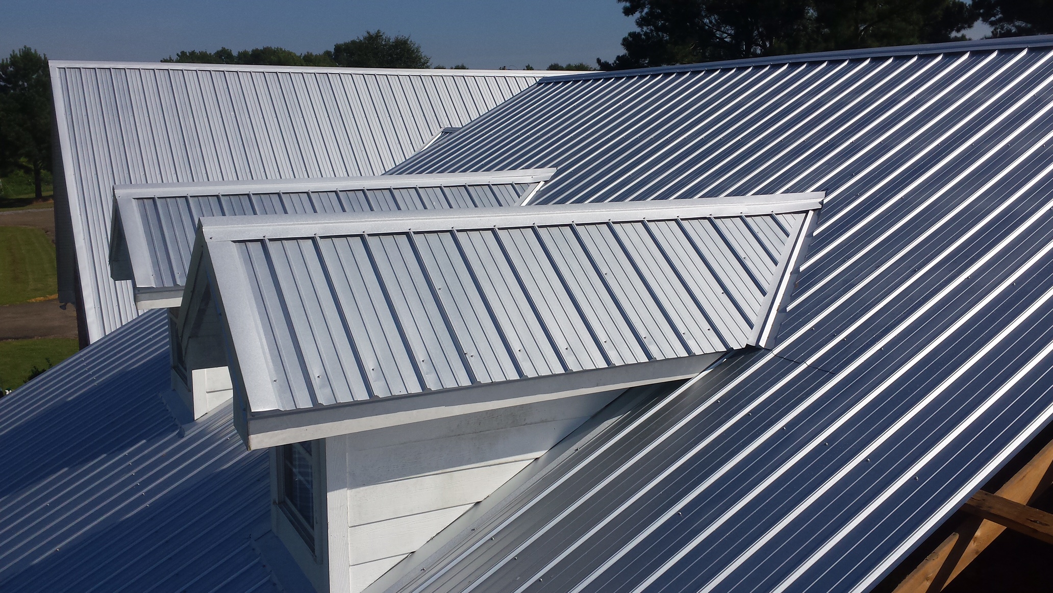 Silver standing seam metal roof with dormer on residential home