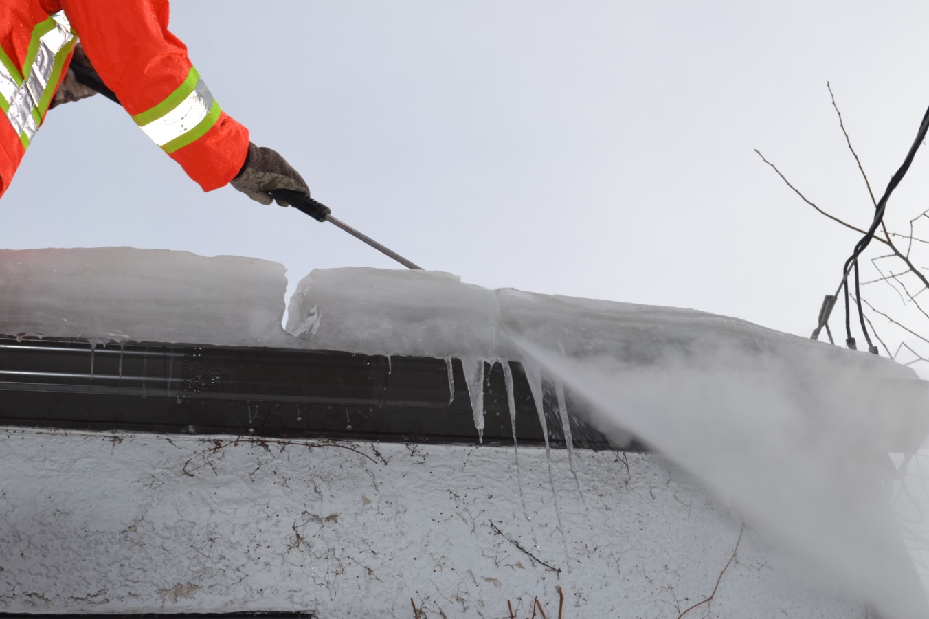 Worker removing ice dams with steam