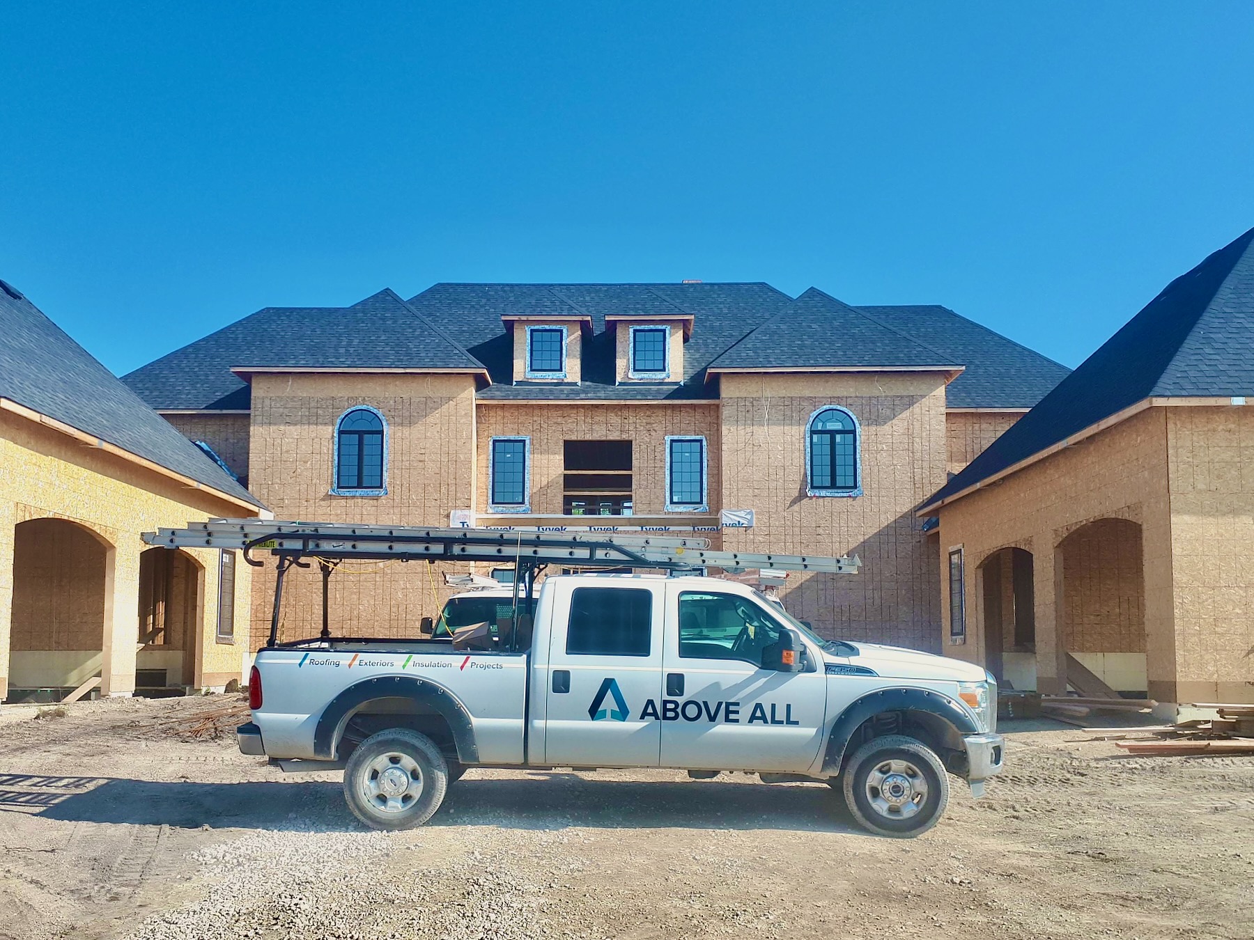 Above All work truck outside a large home under construction