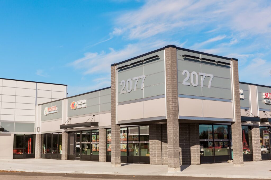 Commercial plaza exterior with grey panels, brick columns and storefronts