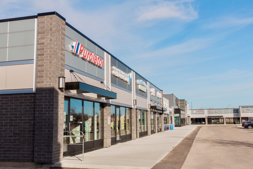 Angled view of strip mall build by Above All Roofing and Exteriors, with retailer store fronts like Purolator.