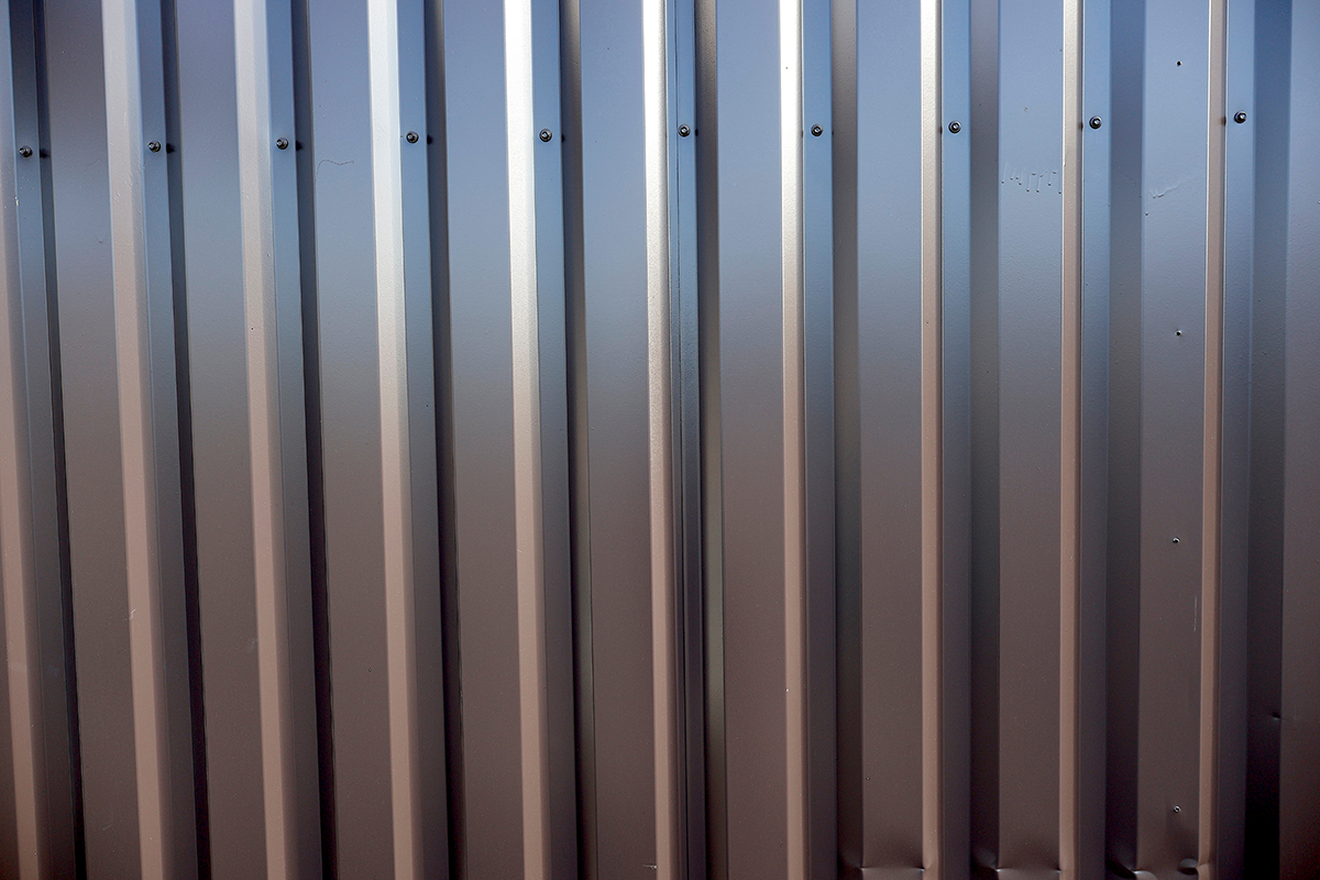 Close-up of grey metal siding panels with vertical ribbed seams.