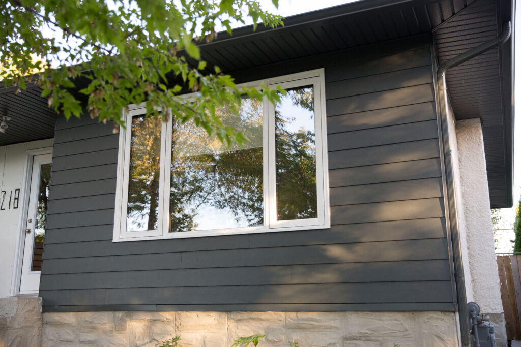 Close-up of dark grey siding surrounding a white-framed window