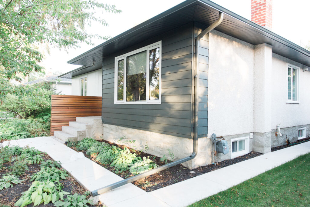 Side view of bungalow showing grey siding, soffits and downspout