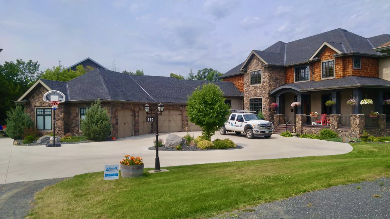 Above All truck parked outside a large stone and cedar home