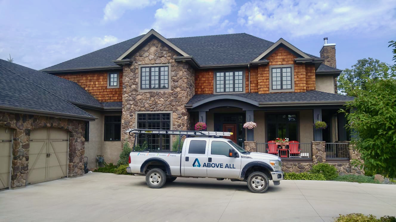 Above All truck parked outside a large stone and cedar home