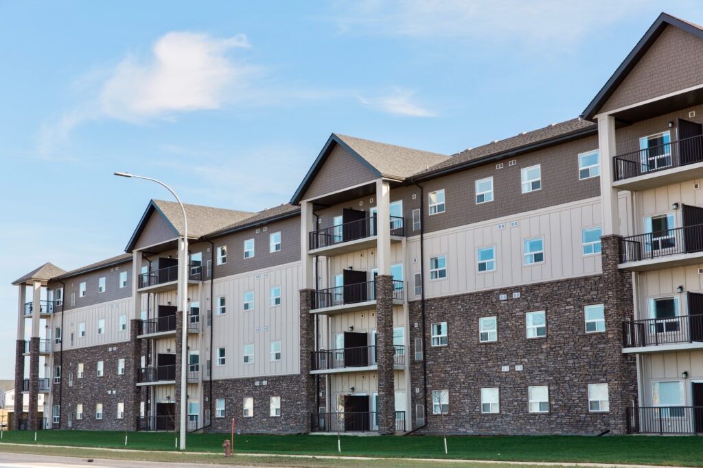 Side vinyl and rock facade of brown and beige four storey Ivy Trails Apartments.
